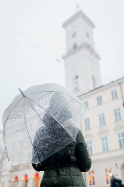 Lviv şehir merkezinde elinde şemsiyeyle gezen bir kadın. Turistler kışın mimariyi severler. Ukrayna 'yı gezmek