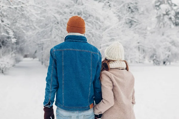 可爱的夫妇在冬季公园散步 男人和女人手牵着手在户外享受着多雪的天气 背景色 — 图库照片