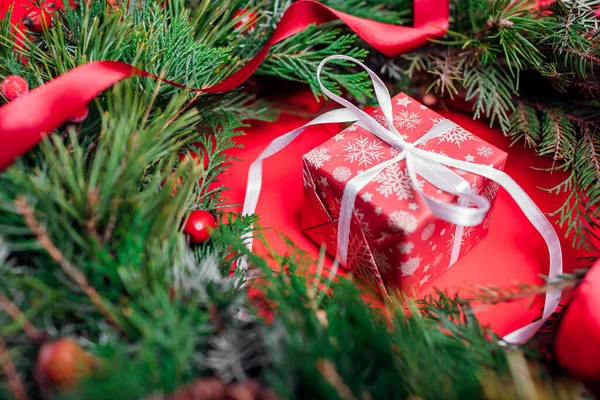 クリスマスと新年のギフトボックスは モミのリースでお祝いの紙とリボンで包まれています 赤を背景にした冬の休日のプレゼント — ストック写真