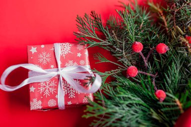 Noel ve Yeni Yıl hediye kutuları, köknar çelengi ve kurdeleye sarılı. Kırmızı arka planda kış tatili için mevcut