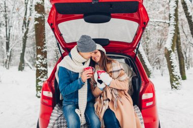 Birbirine aşık bir çift arabanın bagajında oturmuş, karlı kış ormanlarında sıcak çay içip sohbet ediyorlar. İnsanlar yolculuk sırasında dışarıda dinleniyorlar.