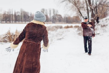 Senior family couple playing snowballs outdoors during snowy winter weather. Elderly people having fun walking. Valentine's day