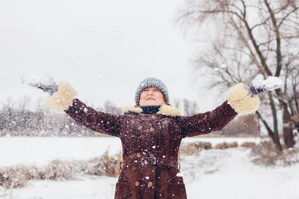 一个快乐的老年妇女在雪地的冬季公园里打雪的画像 散步时在公园里玩得开心 季节性活动 — 图库照片