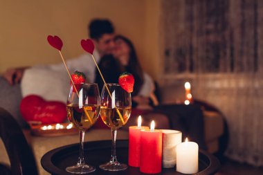 Şenlik şenliklerinin kapanışı çilekli şarap ve kırmızı mumlarla süslenmiş kalp. Sevgililer Günü çifti evde romantik bir akşam yemeği yiyor.