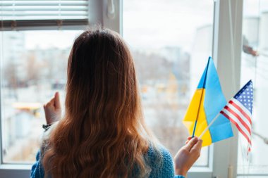 Rusya 'yla savaş sırasında elinde Ukraynalı ve Amerikan bayrakları tutan kadın. ABD desteği. Ukrayna 'da istila. 2022 Rusya 'nın Ukrayna saldırısı