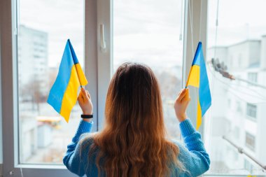 Woman holding Ukrainian yellow and blue flag during war with Russia. Invasion in Ukraine. 2022 Russian attack of Ukraine clipart