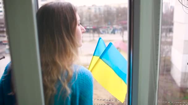 A nő ukrán zászlókat tart otthon az Oroszországgal vívott háború alatt. Invázió Ukrajnában — Stock videók