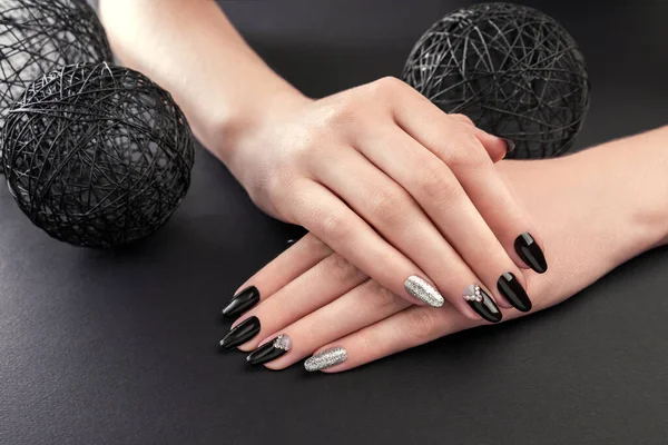 Manucure noire et argent sur fond noir. Mains féminines avec des ongles noirs. Nail art et design — Photo
