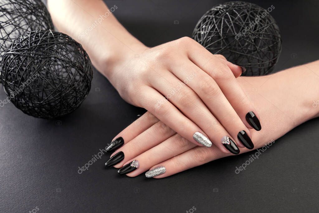 Manicure nera e argento su sfondo nero. Mani femminili con unghie nere. Nail art e design Foto stock di maryviolet 552902570
