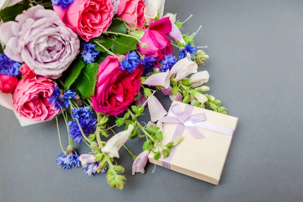 Yaz çiçeğinin buketini kapat tilki eldivenli bekarlığa veda çiçekleri gri arka planda hediye kutusuyla düzenlenmiş. Tatil için sürpriz.
