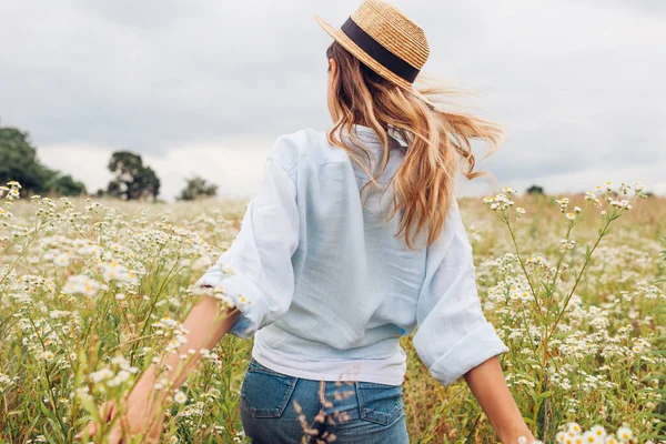 Back view of woman running in blooming field of wildflowers. Harmony with nature. Enjoying summer meadow landscape