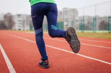 Sonbaharda spor sahasında koşan zayıf formda bir bayan sporcu. Spor ayakkabılarını ve açık havada kadın bacaklarını kapat. Aktif sağlıklı yaşam tarzı