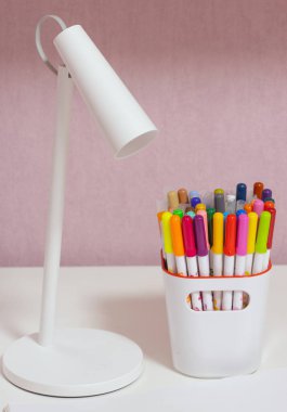 Beyaz bir kabın içinde çok renkli işaretler ve beyaz masa lambası