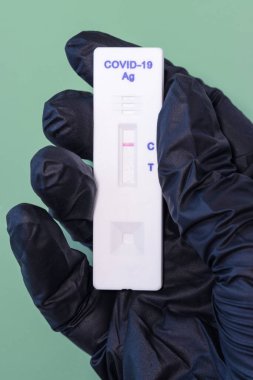 Siyah eldivenli bir el, koronavirüs için negatif bir test tutar.
