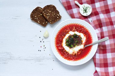 borsch with sour cream and herbs in a white plate