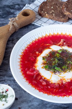 borsch with sour cream and herbs in a white plate