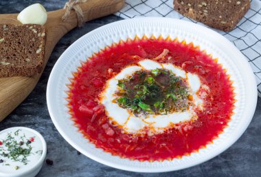 borsch with sour cream and herbs in a white plate