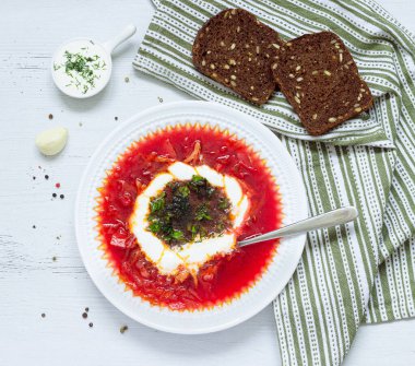 borsch with sour cream and herbs in a white plate