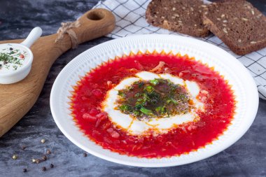 borsch with sour cream and herbs in a white plate