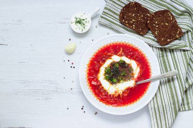 borsch with sour cream and herbs in a white plate, copy space