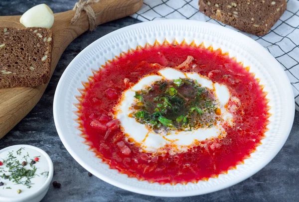 borsch with sour cream and herbs in a white plate