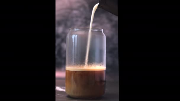 Milch wird in einem Glas in Kaffee gegossen — Stockvideo