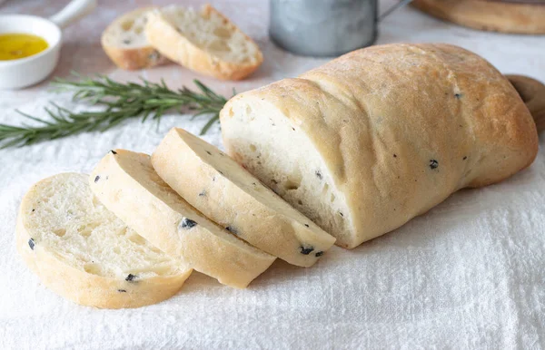 Ciabatta de trigo en rodajas con aceitunas sobre una toalla blanca. Pan casero de trigo — Foto de Stock