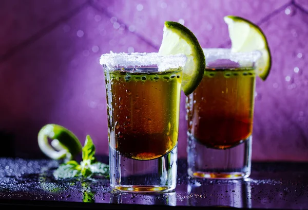 Due cocktail di shot marroni guarniti con lime e sale. sul bancone — Foto Stock