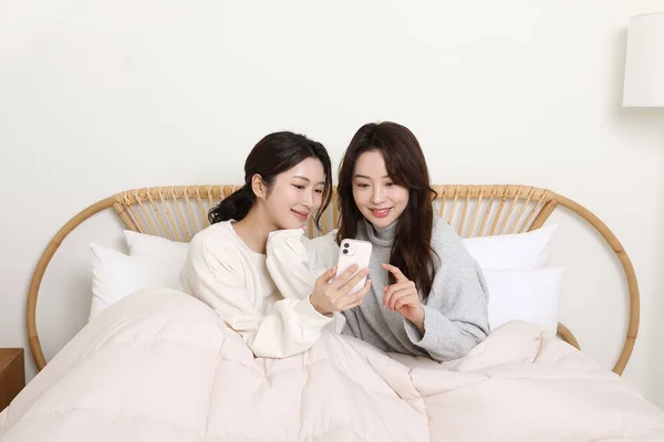 Vintersäsongskoncept Två Vackra Asiatiska Koreanska Kvinnor Tittar Sina Smartphones Sängen — Stockfoto