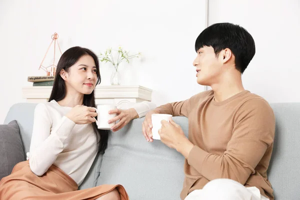 甜蜜的亚裔韩国夫妇在沙发上喝茶 — 图库照片