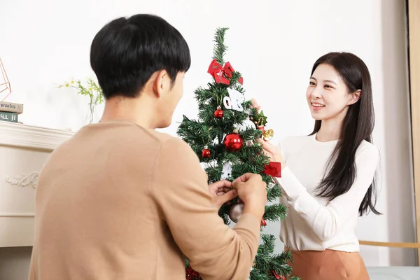 室内にクリスマスツリーを飾るアジアの韓国のカップル — ストック写真