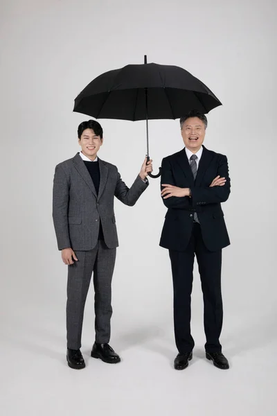 business concept Korean Asian old and young men holding an umbrella