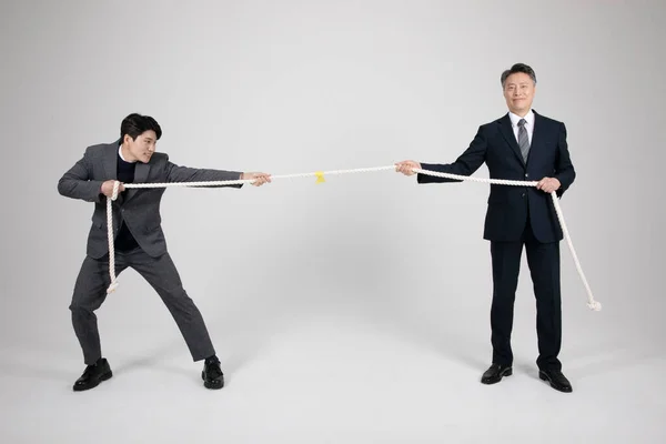 事業概念朝鮮系アジア人の老人と青年が綱引きをする — ストック写真