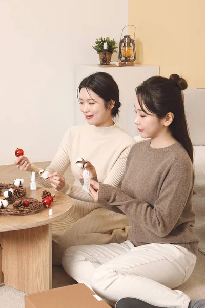 アジア系韓国人女性が屋内でクリスマスリースを作るのに — ストック写真