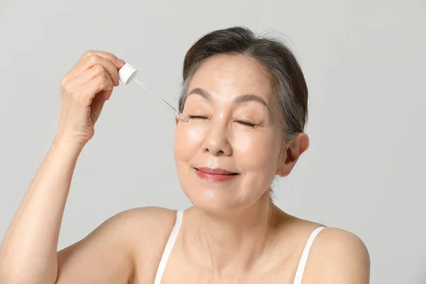 Asian Korean senior woman, basic skin care beauty concept in studio