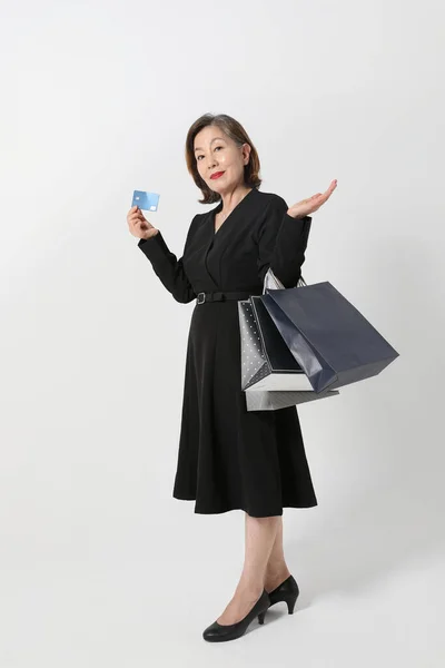 时髦的亚裔韩国老年妇女 手持信用卡和购物袋 — 图库照片