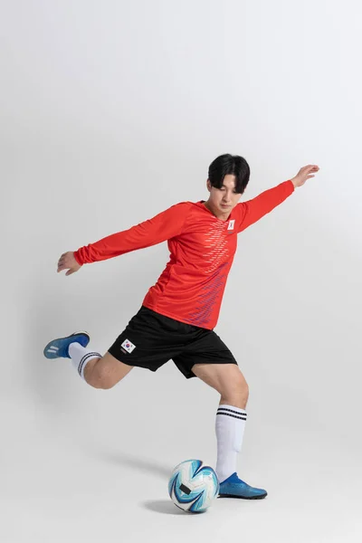 サッカーのスポーツ選手アジア系韓国人男性スタジオの背景に動きがある — ストック写真