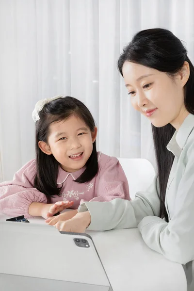 アジア系韓国人の母親と娘がタブレットでオンライン授業を受ける — ストック写真