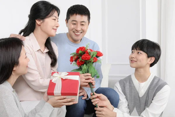カーネーションと贈り物を持つ親の日のアジアの韓国家族のお祝い — ストック写真