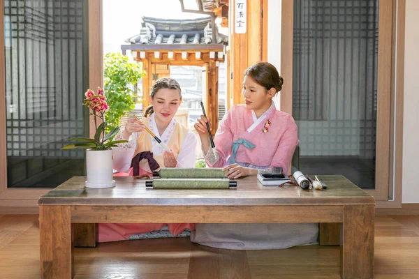 Korean and Caucasian girls Experiencing traditional calligraphy in Hanok, Korean traditional house