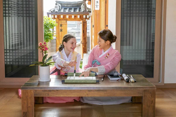 Korean and Caucasian girls Experiencing traditional calligraphy in Hanok, Korean traditional house