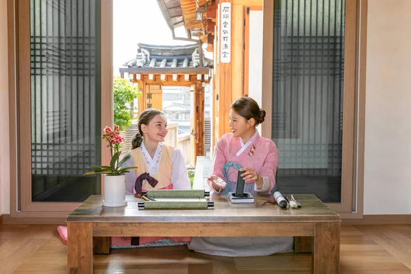 Korean and Caucasian girls Experiencing traditional calligraphy in Hanok, Korean traditional house