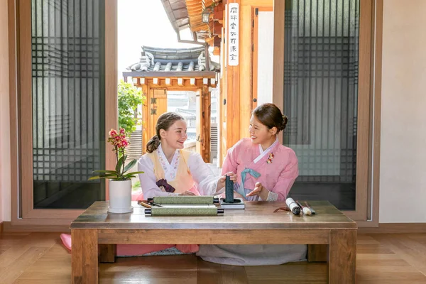 Korean and Caucasian girls Experiencing traditional calligraphy in Hanok, Korean traditional house