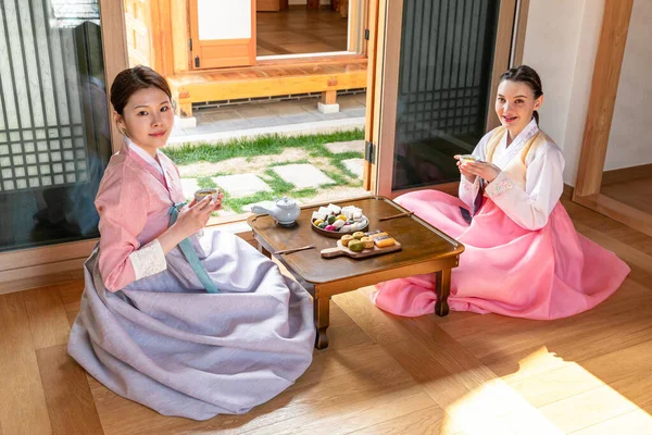Korean and Caucasian girls experiencing traditional tea ceremony in Hanok, Korean traditional house