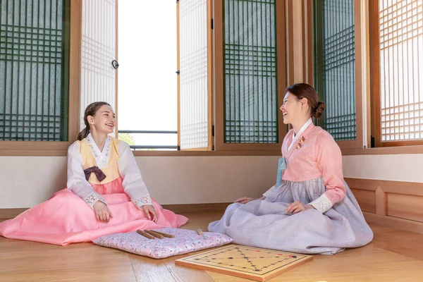 Korean and Caucasian girls wearing Hanbok playing Yut, Korean traditional board game