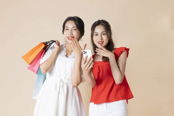 スマートフォンとショッピングバッグをスタジオに設置した2人の美しい韓国人女性 — ストック写真