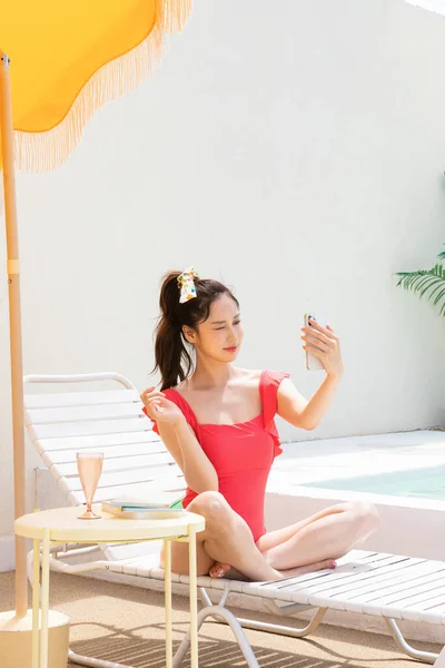 夏休みのコンセプト_韓国の美しいアジアの若い女性取りますA自撮り座ってザ サンベッド — ストック写真