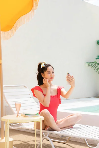 夏休みのコンセプト_韓国の美しいアジアの若い女性取りますA自撮り座ってザ サンベッド — ストック写真