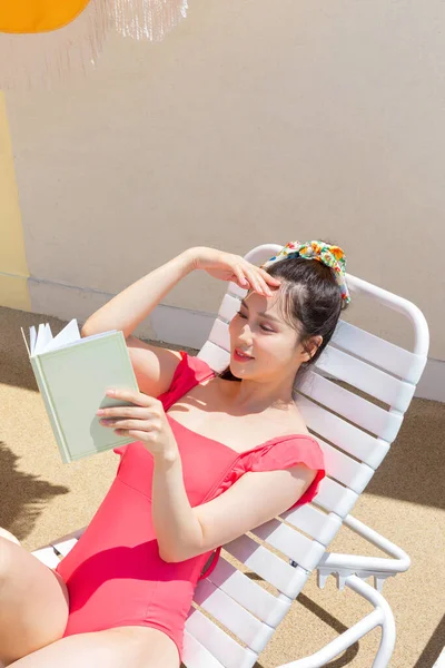 夏休みのコンセプト_韓国の美しいアジアの若い女性が日焼けの上に横たわる本を読んで — ストック写真