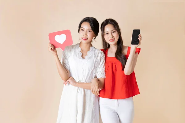 友達と夏休み旅行のコンセプトシリーズ_韓国の美しいアジアの若い女性がハート型のパネルとスマートフォンを持っています — ストック写真